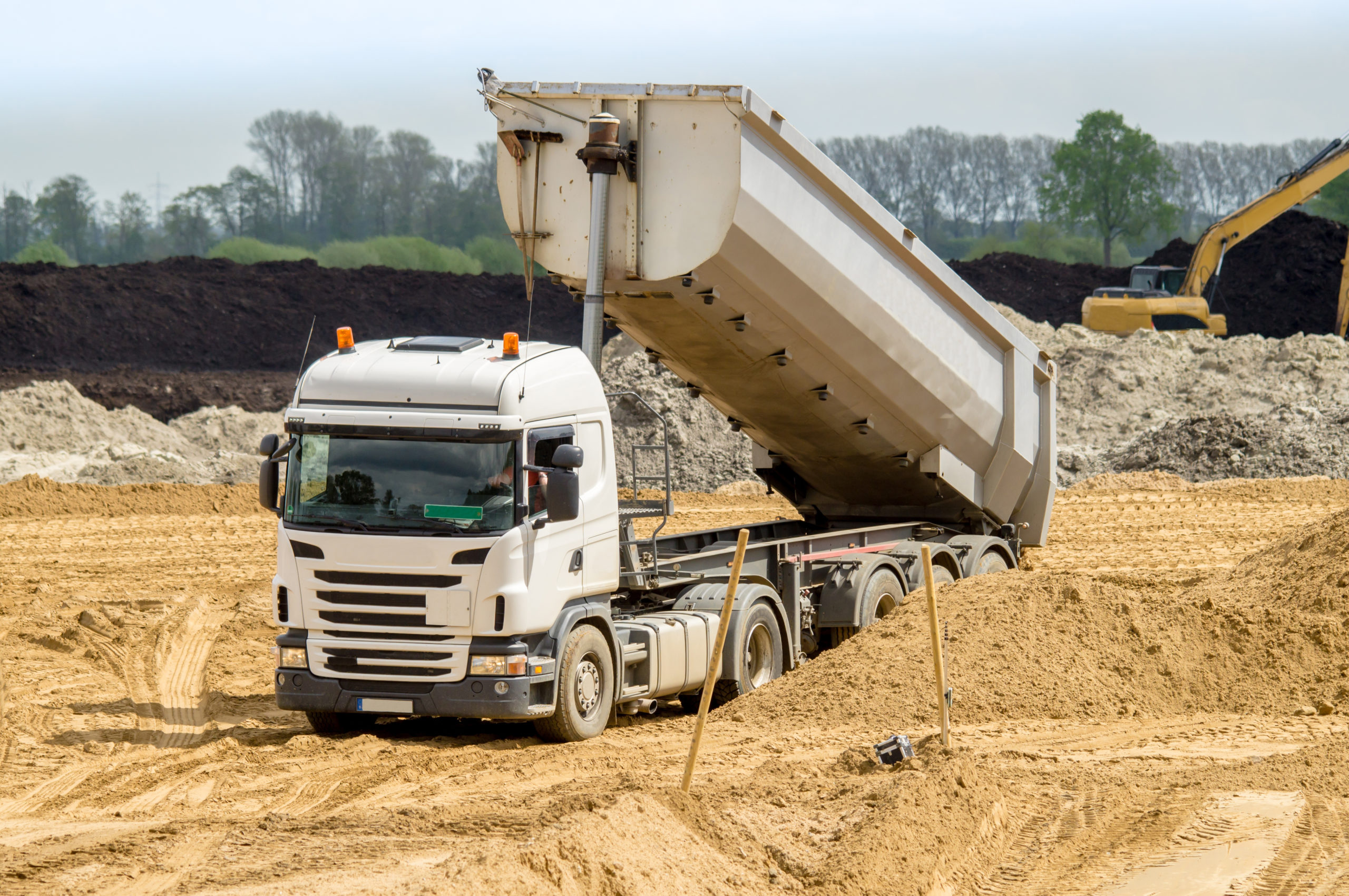 Straßenbau - Lastkraftwagen mit Auflieger kippt Sand ab